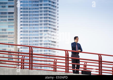 Porträt des chinesischen Geschäftsmann auf Brücke in Panama-Stadt mit Skyline im Hintergrund stehen, Telefon Anruf Stockfoto