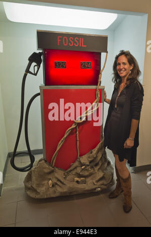 Massapequa, New York, USA. 18. Oktober 2014. LORI HOROWITZ, Künstler und Galerist, ist stand neben ihrer Skulptur destilliertem Leben, eine glühende rote Zapfsäule mit fossilen oben, während das Studio 5404 Kunstraum Vernissage zur Ausstellung auf der Straße geschrieben. Umgebung ist das Thema der Mixed-Media-Installation, die aus Holz, Kunststoff und Pappmaché gefertigt ist, und die Ausstellung zeigt neue Werke von aufstrebenden und aufstrebenden lokalen und New York Künstler. Studio 5404 ist an der South Shore von Long Island. Bildnachweis: Ann Parry/ZUMA Draht/Alamy Live-Nachrichten Stockfoto