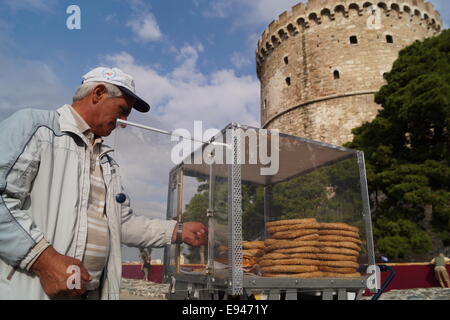 Thessaloniki, Griechenland. 19. Oktober 2014.  Eine traditionelle Koulouri Verkäufer Stand vor der "größten Koulouri" Bäcker aus Nordgriechenland errichtet eine 150 Meter lange "Koulouri" (eine traditionelle griechische Sesam-beschichtete Brot) in der zweitgrößten Stadt Thessaloniki, Griechenland.  Die Bäcker umgeben der Stadt ikonischen weißen Turm um einen Guinness-Rekord der weltweit längste Koulouri je gemacht Credit zu erreichen: Orhan Tsolak Alamy Live News Stockfoto