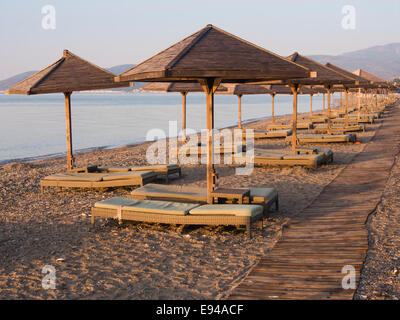 Am frühen Morgen am Strand von Doryssa Resorthotel in Pythagorion Samos Insel Griechenland, goldenen Licht und leeren Sonnenliegen erwartet Stockfoto