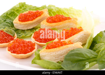 Roter Kaviar in Gebäck und Salat auf Teller. Stockfoto