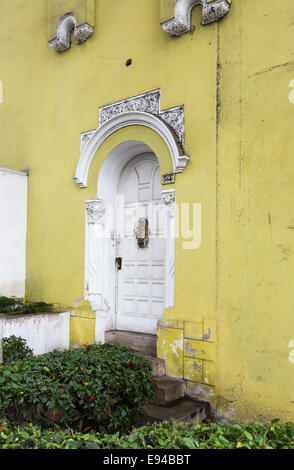 Weiße Tür- und Stuck mit abblätternden Lack in einer gelben Wand eines vernachlässigten vorstädtischen Kolonialhauses im Vorort Miraflores, Lima, Peru Stockfoto