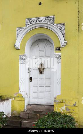 Weiße Tür- und Stuck mit abblätternden Lack in einer gelben Wand eines vernachlässigten vorstädtischen Kolonialhauses im Vorort Miraflores, Lima, Peru Stockfoto