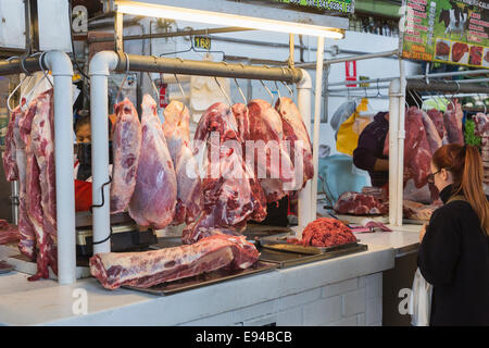 Weibliche Kunden bei einem typischen kleinen Metzger mit großen hängenden Verbindungen von frischem Fleisch stall suchen, Surquillo Markt, Miraflores, Lima, Peru Stockfoto