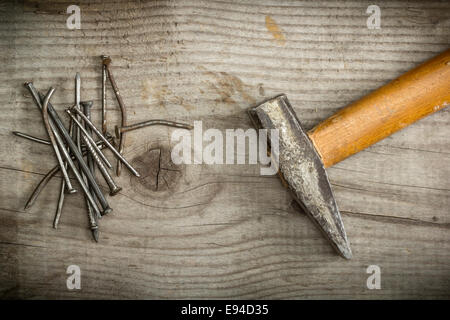 Alte rostige Nägel und Hammer auf hölzernen Hintergrund Stockfoto