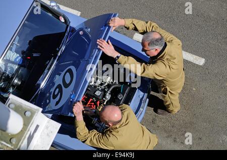 Overhead Schuss von zwei Mechanikern in der Boxengasse in Goodwood Öffnung der Motorhaube eines Rennwagens Fiat-Klassikers. Stockfoto