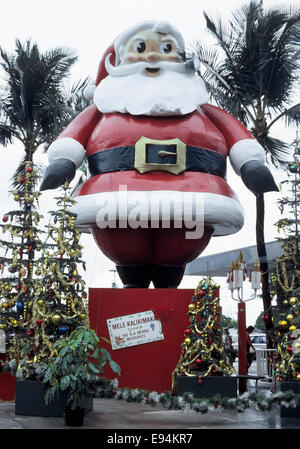 Eine hoch aufragenden Weihnachtsmann-Display wünscht Shopper Hawaiian Frohe Weihnachten (Mele Kalikimaka) an das Ala Moana Center in Honolulu, Oahu, Hawaii, USA. Stockfoto