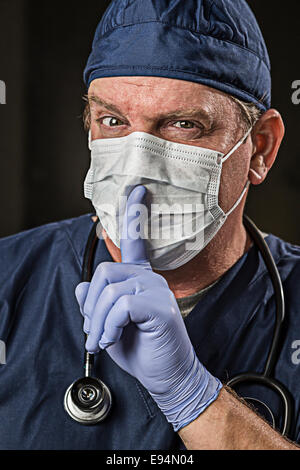 Geheimnisvolle Arzt oder Krankenschwester mit Finger in Front of Mouth tragen Schutzkleidung tragen und Stethoskop. Stockfoto