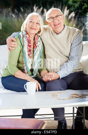 Ältere Mann, sitzend mit Arm um Frau auf Couch Stockfoto