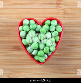 Frisch gefrorenen Erbsen in einer Herz-Schüssel. Close-up. Stockfoto