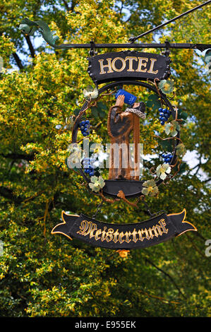 Hängende Ladenschild des Hotel Meistertrunk, hinter einem blühenden Sommer Linde (Tilia Platyphyllos), Rothenburg Ob der Tauber
