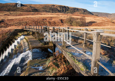 Steg über das Stauwehr am Crowden in Longdendale mit Blick auf die bunte Winterlandschaft. Stockfoto