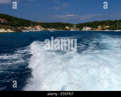 Blick aus dem hinteren Teil eines Bootes Beschleunigung weg von der Bucht Fiscardo auf die Insel Kefalonia in Griechenland Stockfoto