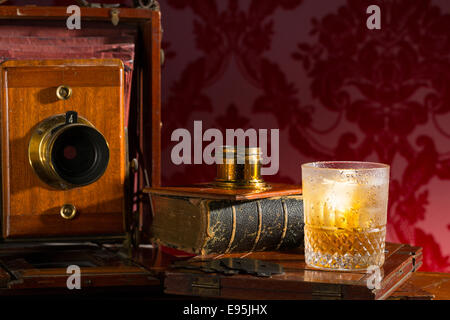 Alten altmodische Blasebalg Platte Kamera Stillleben mit einem Glas Whiskey und Eis Stockfoto