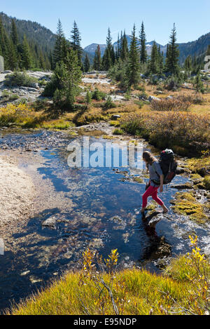 Frau, die über einen Bach auf einem Rucksack Reise in Oregon Wallowa Mountains. Stockfoto