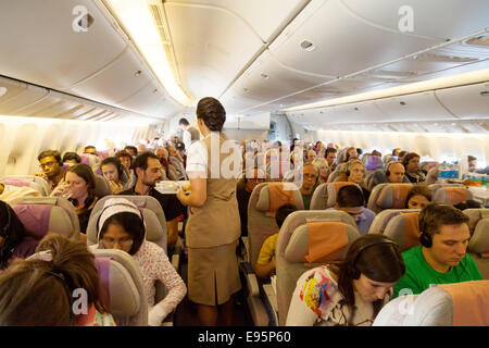 Passagiere und Stewardess an Bord eines Flugzeugs Emirates Airline; die Kabine einer Boeing 777-Flug von London nach Dubai Stockfoto