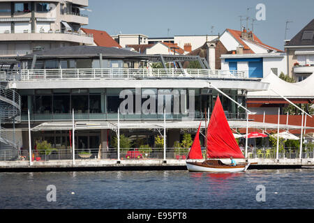 Im Sommer, ein kleines rotes Segelboot auf dem See Allier (Vichy). Petit voilier À Voiles Rouges Sur le Lac d ' Allier, À Vichy. Stockfoto