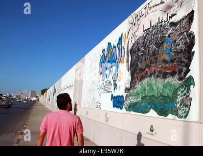 Tripoli, Libyen. 20. Oktober 2014. Tripolis Bürger Spaziergänge entlang der Wand gemalt mit Graffiti Darstellung des 2011-Krieges, der ehemaligen Führer Libyens Muammar Gaddafi in Tripolis, Libyen, am 20. Oktober 2014 gestürzt. Libyen ist am Montag den dritten Jahrestag des Todes von Gaddafi, gefangen genommen und getötet von den Rebellen in seiner Heimatstadt Sirte nach einer achtmonatigen Revolte gegen seine vier Jahrzehnten Herrschaft durch NATO-Luftangriffe gesichert. Bildnachweis: Hamza Türkei/Xinhua/Alamy Live-Nachrichten Stockfoto