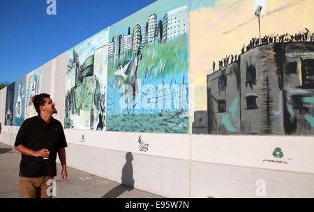 Tripoli, Libyen. 20. Oktober 2014. Tripolis Bürger Spaziergänge entlang der Wand gemalt mit Graffiti Darstellung des 2011-Krieges, der ehemaligen Führer Libyens Muammar Gaddafi in Tripolis, Libyen, am 20. Oktober 2014 gestürzt. Libyen ist am Montag den dritten Jahrestag des Todes von Gaddafi, gefangen genommen und getötet von den Rebellen in seiner Heimatstadt Sirte nach einer achtmonatigen Revolte gegen seine vier Jahrzehnten Herrschaft durch NATO-Luftangriffe gesichert. Bildnachweis: Hamza Türkei/Xinhua/Alamy Live-Nachrichten Stockfoto