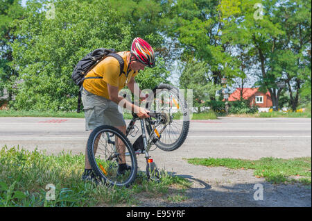 Reife Radfahrer, die Reparatur auf der Straße Stockfoto
