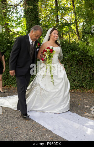 Vater zu seiner Tochter den Gang hinunter während der Hochzeit Zeremonie an Marin Kunst und Garten Center, Stadt Ross, Marin County, Kalifornien Stockfoto