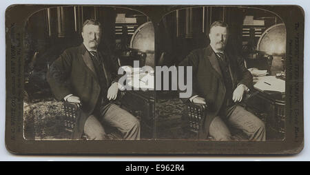Dieses Bild zeigt Präsident Theodore Roosevelt an seinem Schreibtisch, wahrscheinlich während seiner Amtszeit. Das Foto zeigt Roosevelt in einem Moment der Besinnung oder Arbeit, umgeben von Globen und anderen Bürogegenständen, die seine Führungsrolle in der amerikanischen Geschichte zeigen. Stockfoto