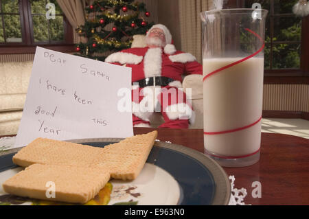 Schlafen in einem Stuhl dabei seine Lieferungen Armen Santa Stockfoto