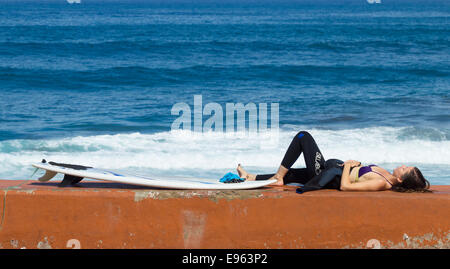 Weibliche Surfer mit Surfbrett an Wand La Cicer Strand Las Canteras, Las Palmas, Gran Canaria. Kanarische Inseln, Spanien Stockfoto