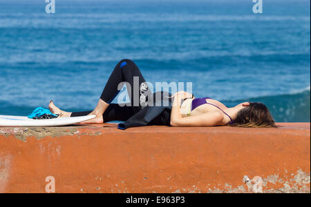 Weibliche Surfer mit Surfbrett an Wand La Cicer Strand Las Canteras, Las Palmas, Gran Canaria. Kanarische Inseln, Spanien Stockfoto