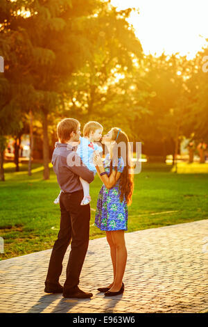 Glückliche Familie Mutter, Vater und Tochter gehen im Herbst Park. Tochter hält einen Lutscher Stockfoto