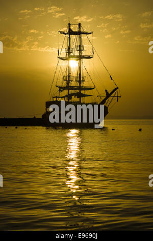 Sonnenuntergang über dem Meer und ein einsamer Segelschiff in der Bucht. Stockfoto