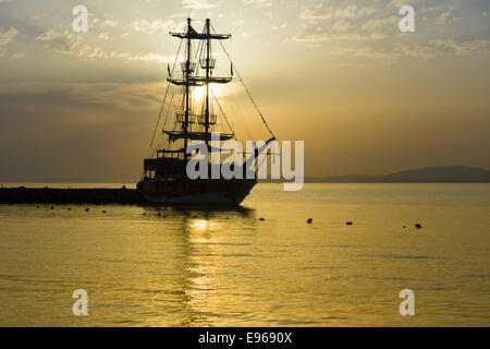 Sonnenuntergang über dem Meer und ein einsamer Segelschiff in der Bucht. Stockfoto