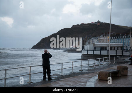 Aberystwyth, Großbritannien 21. Oktober 2014. Sturm-Gonzalo trifft Aberystwyth mit Windgeschwindigkeiten von bis zu 70 km/h. Ein Mann fotografiert die Wellen, wie Flut nähert. © Jon Freeman / Alamy Stockfoto