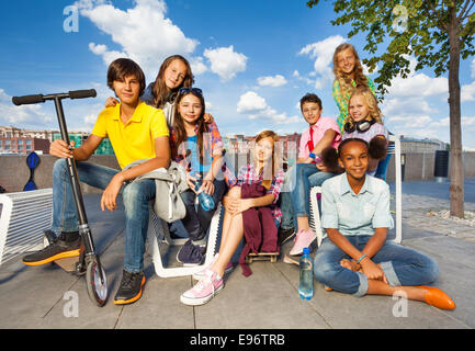 Internationale Kinder sitzen auf Stühlen mit Roller Stockfoto