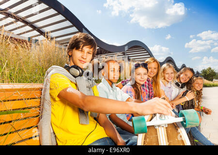 Mann mit Mädchen sitzen auf der Bank und hält skateboard Stockfoto