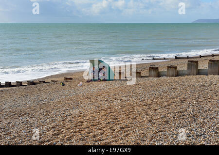 Ein älteres paar bergende von der Meeresbrise in Bexhill am Meeresstrand. East Sussex Stockfoto