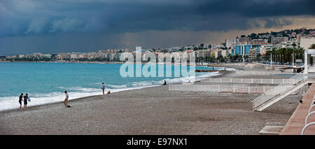 Touristen am Strand und dunklen bedrohlichen Regenwolken über der Stadt Nizza entlang der Côte d ' Azur, Côte d ' Azur, Alpes-Maritimes, Frankreich Stockfoto