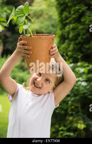 Kleines Mädchen, Gartenarbeit, Topfpflanze in den Händen halten Stockfoto