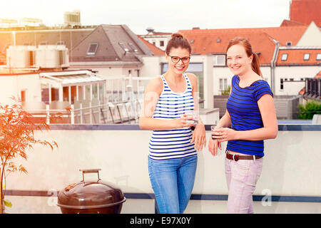 Zwei junge Frauen mit einem Drink auf Balkon, München, Bayern, Deutschland Stockfoto