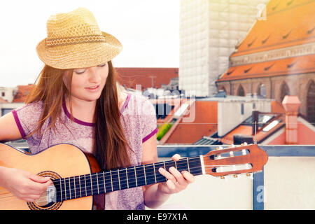 Junge Frau, die Gitarre auf Balkon, München, Bayern, Deutschland Stockfoto