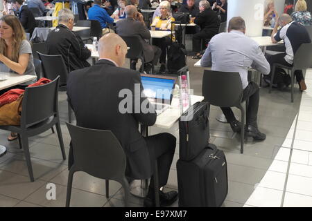 Geschäftsmann auf Laptop am Sydney Flughafen Abflughalle Terminal 2 Halle Viertel mit Geschäften und Restaurants, New South Wales, Australien Stockfoto