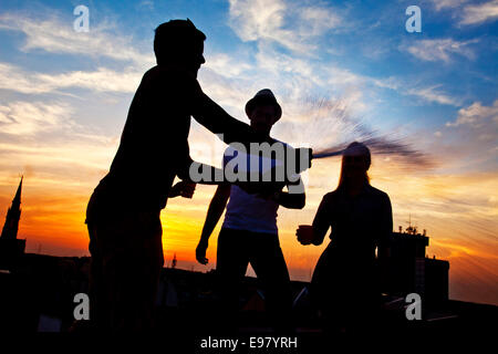 Jugendliche herumalbern mit Flasche Champagner bei Sonnenuntergang Stockfoto