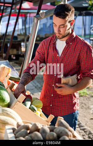 Junger Mann kaufen Gemüse am Marktstand Stockfoto