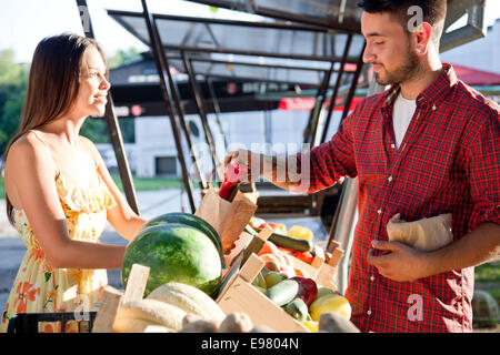 Junger Mann kaufen Gemüse am Marktstand Stockfoto