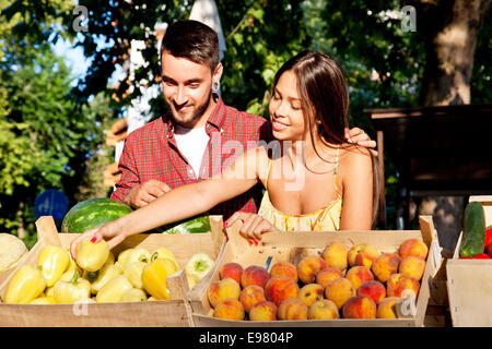 Junges Paar verkaufen Obst und Gemüse am Marktstand Stockfoto