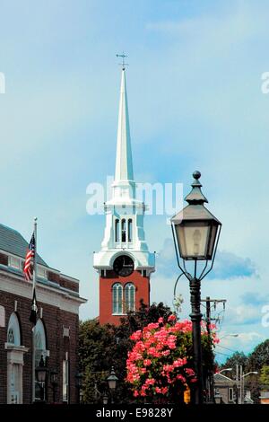 Blick auf ein Zeitdokument Backstein und weißen Turm mit Uhr und eine Straßenlaterne Zeitdokument und Blumen im Vordergrund. Stockfoto