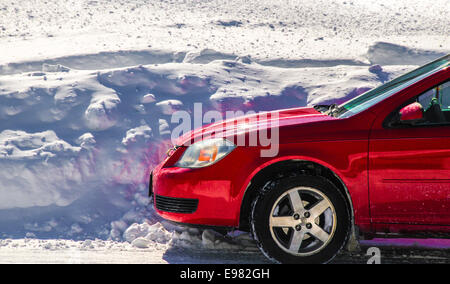 Der leuchtend rote sauber glänzend Vorderwagen ist im vorderen 5 Fuß Schnee Bank weißen Schnee blauen Schatten geparkt. Schnee füllt vollständig Bild Stockfoto