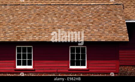 Blick auf eine frisch gestrichene helle rote Scheune auf einem Bauernhof Kuh mit hellen weißen gerahmte Fenster an einem sonnigen Tag. Stockfoto