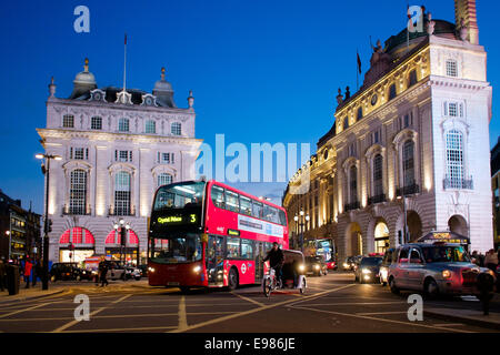 London Piccadilly Circus in der Abenddämmerung mit tiefblauem Himmel und rote Bus und Rikscha im Vordergrund Stockfoto