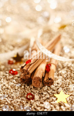 Zimt-Sticks mit einem Band auf goldenem Hintergrund für Weihnachten-Konzept. Stockfoto